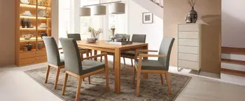 Esszimmer mit rechteckigem Holztisch, vier grauen Polsterstühlen und beleuchtetem Vitrinenschrank links neben Treppe.